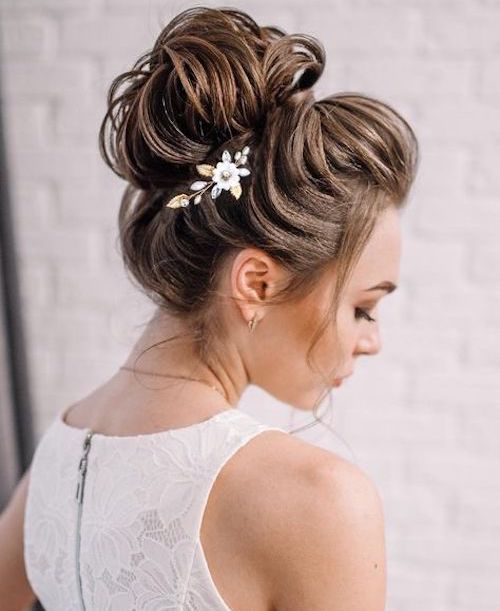 a glam loose top knot with a bump and a floral hair piece is a chic and catchy hairstyle idea