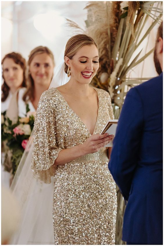 a gold sequin wedding dress with a deep V-neckline, wide sleeves and a cathedral veil is a chic and glam idea
