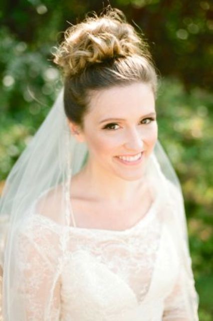 a lovely wrapped and curled top knot with some volume and a cathedral veil attached for a classic wedding