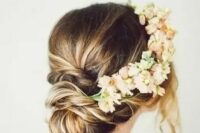 a low updo with a twisted low bun and neutral and blush blooms and some locks down to frame the face is a beautiful idea for a boho bride