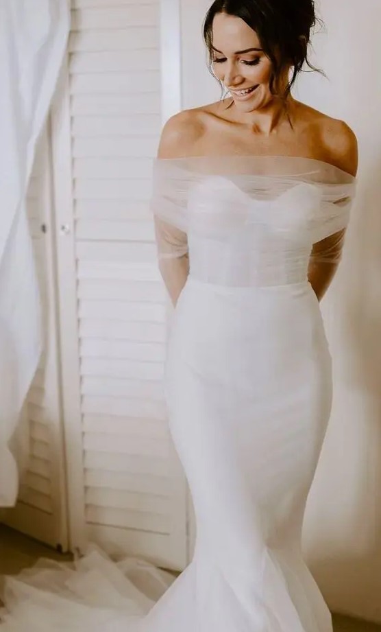 a mermaid strapless wedding dress with a corset bodice and a tulle dress topper with long sleeves for a delicate detail