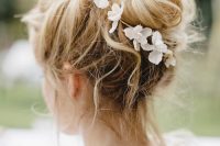 a messy and volumetric top knot with some locks down and white blooms is a catchy and chic idea to rock