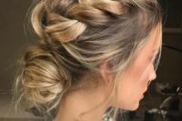a messy braided low bun updo with loose messy braids on top the head for a modern and trendy look