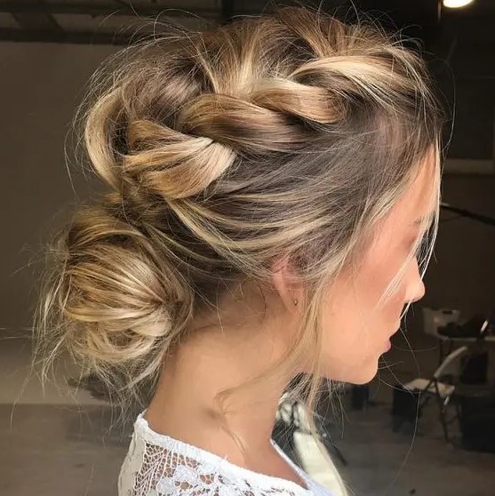 a messy braided low bun updo with loose messy braids on top the head for a modern and trendy look