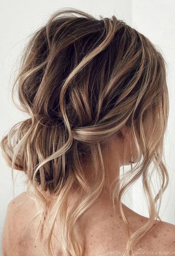 a messy wavy low bun with a messy wavy top and some locks down is a cool and lovely idea for a wedding, it looks effortlessly chic