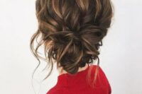 a messy wavy updo with a low twisted bun, some locks down and a volume on top