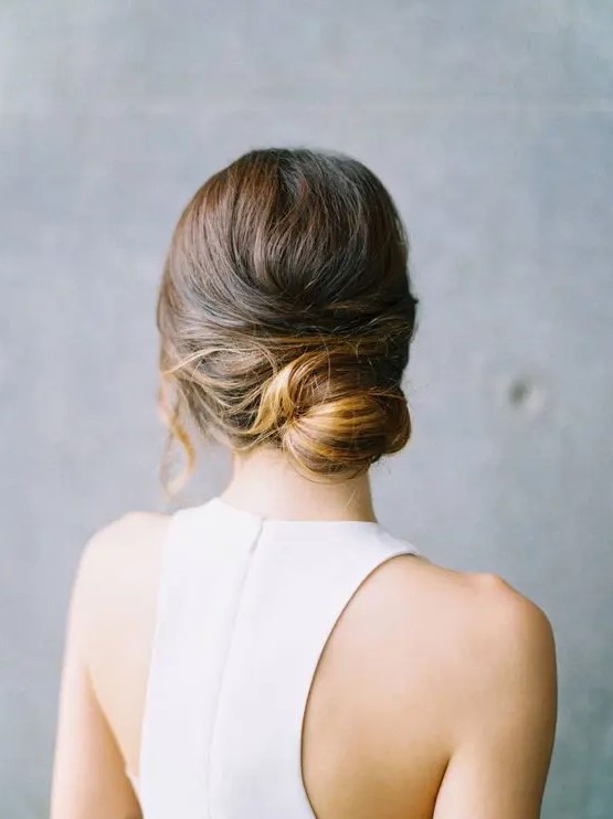 a modern low bun with a bump and locks down is a refined and elegant hairstyle for a minimalist bride