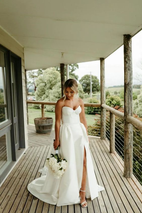 a modern strapless plain wedding ballgown with a thigh high slit, white strappy shoes for a modern and chic look