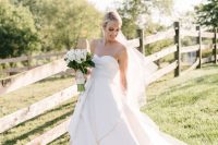 a plain strapless wedding ballgown with a layered skirt and a train plus a veil are a beautiful combo for a modern refined wedding