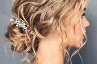 a refined and wavy messy low bun with a wavy top, locks down and an embellished hairpiece is a chic idea