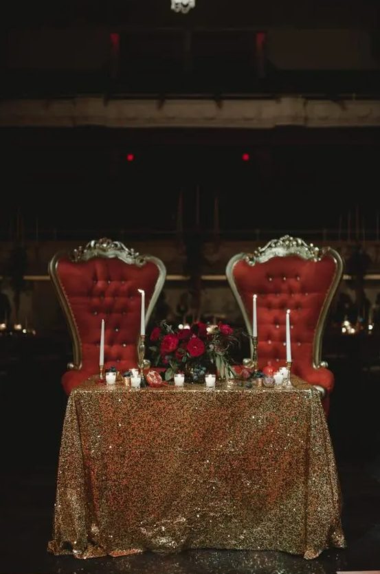 a refined vintage space with a gold sequin tablecloth, a red floral centerpiece and refined red chairs is wow