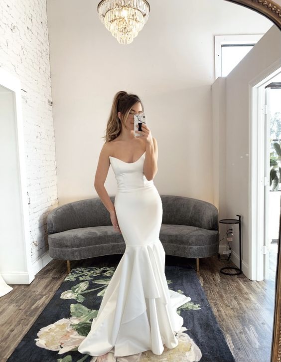 a sexy strapless memraid wedding dress with a cutout neckline, a layered skirt with a train is a glam and cool solution