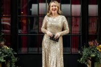 a shiny NYE wedding guest outfit with a gold sequin midi dress with long sleeves, black shoes and a small black clutch
