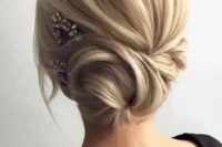 a side twisted low bun with some locks down and a rhinestone hairpiece on one side