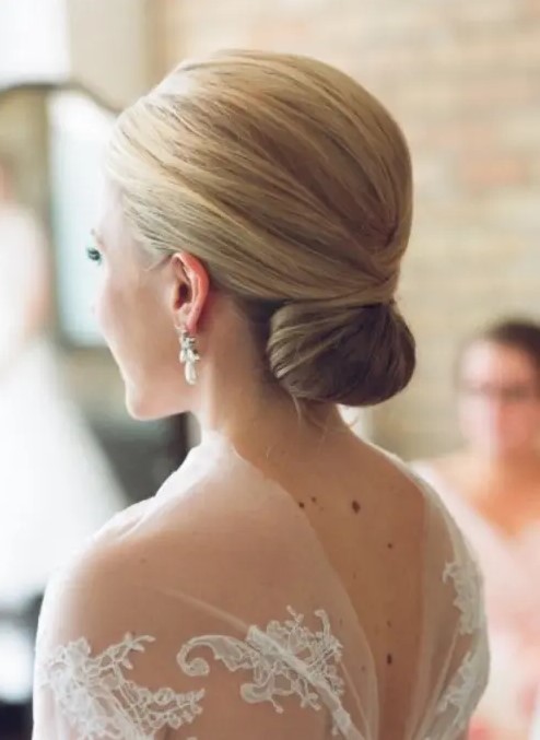 a sleek minimalist wedding twisted low bun with a sleek volume on top is a stylish option for many bridal looks