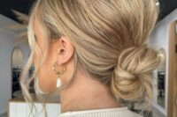 a super messy and cool wedding low ballerina bun with a messy bump on top and face-framing locks is wow