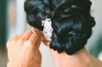 a twisted low bun with a wavy top and a rhinestone hairpiece is a chic and beautiful hairstyle to try