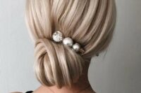 a very elegant low bun with a volume on top and a pearly hairpin is a stylish idea for bride looking for elegance