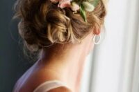 a wavy and messy low bun with a textured and dimensional top, with fresh pink roses and greenery looks classic and chic