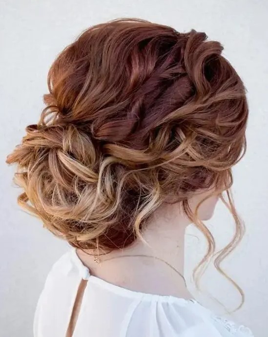 a wavy messy updo with locks to frame the face and a low bun plus an ombre effect is a chic and lovely idea for a wedding