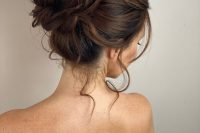 a wrapped and messy top knot with a bump on top and some locks down is a chic and catchy idea