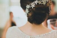 an elegant twisted low bun with a sparkling flower hairpiece and a sleek and tight top for a more formal bridal look