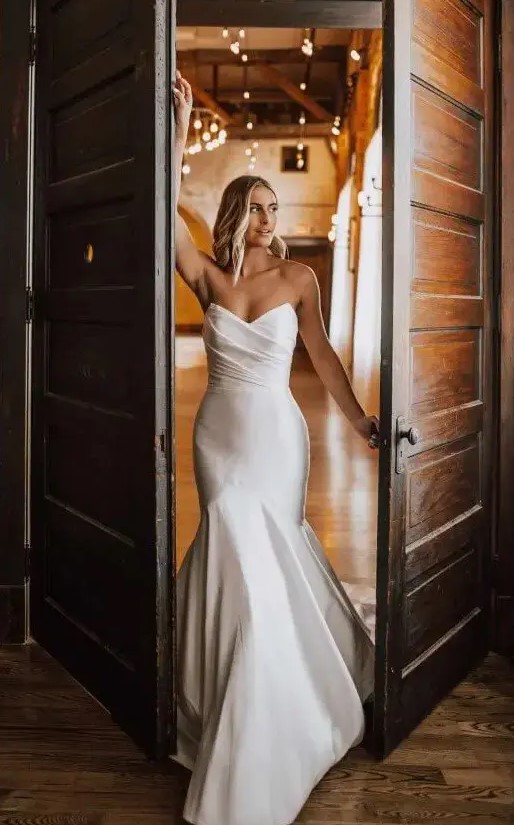 An exquisite modern strapless wedding dress with a mermaid silhouette, a draped bodice and a train is jaw dropping