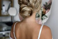 an eye-catchy wedding updo with a twisted low bun, a wavy top and some little waves on top to make it cooler