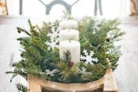02 a beautiful winter wedding centerpiece of a basket with evergreens and a breadbowl with evergreens and candles plus pinecones and snowflakes