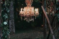 02 a gorgeous wild boho wedding arch of branches, foliage, bright blooms and with a glam chandelier to light up the space