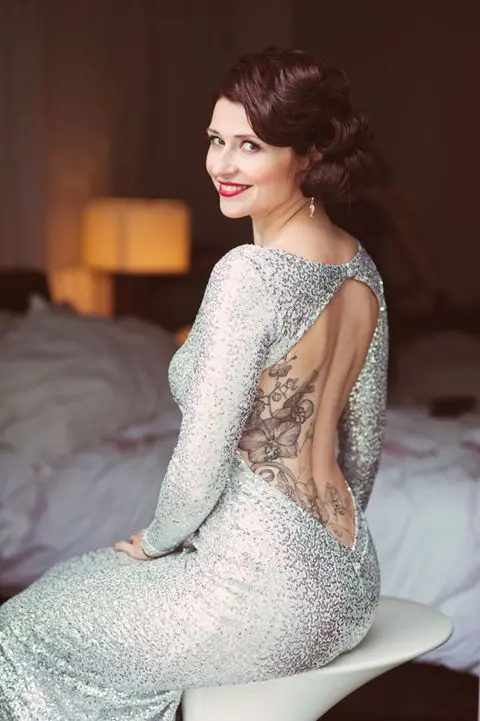 a backless silver sequin wedding dress with long sleeves to show off the bride's tattoes