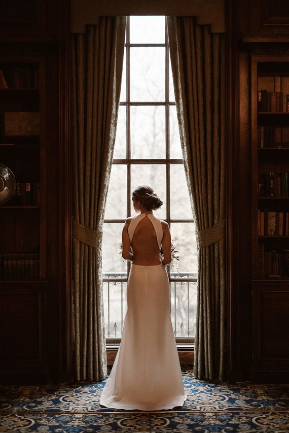 a modern fitting wedding dress with a halter neckline and an open back with a geometric cutout back