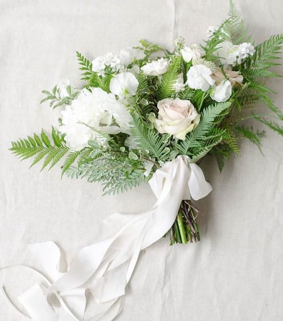 a chic textural white winter wedding bouquet with ferns and white ribbons