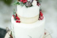 06 a Christmas wedding cake topped with fake greenery, berries, pinecones and burlap ribbons for a snowy feel