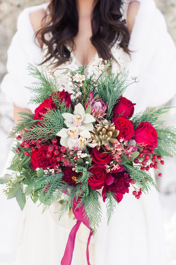 a lush Crhsitmas wedding bouquet with holly berries, bold blooms, orchids, succulents and evergreens