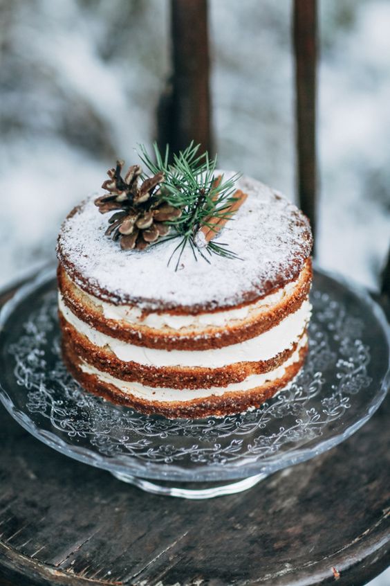 a naked wedding cake with sugar powder, evergreens, pinecones and cinnamon sticks for a Scnadi winter wedding