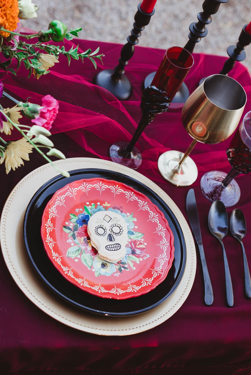 Colored glasses, dark cutlery and sugar skull cookies marked each place setting