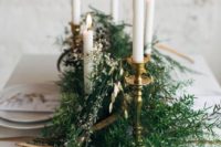 10 a simple winter wedding centerpiece of evergreens, little blooms and candles in candle holders for a Nordic wedding