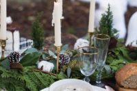 11 a winter wedding centerpiece of evergreens, ferns, snowy pinecones, cotton and candles in candle holders for a Christmassy table setting