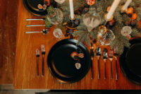 13 The table setting was done with evergreens, blackberries, blueberries, pomegranates and candles plus modern black chargers and plates