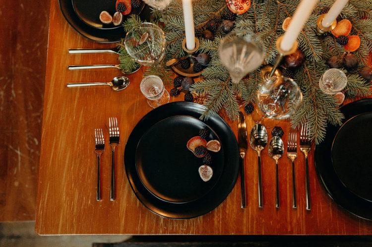 The table setting was done with evergreens, blackberries, blueberries, pomegranates and candles plus modern black chargers and plates