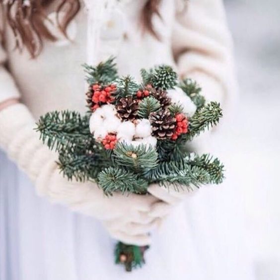 a simple rustic wedding bouquet with evergreens, cotton, pinecones and holly berries