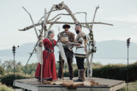 13 a viking-inspired wedding ceremony arch of driftwood on a platform with a fake animal skin and runs hanging on the arch
