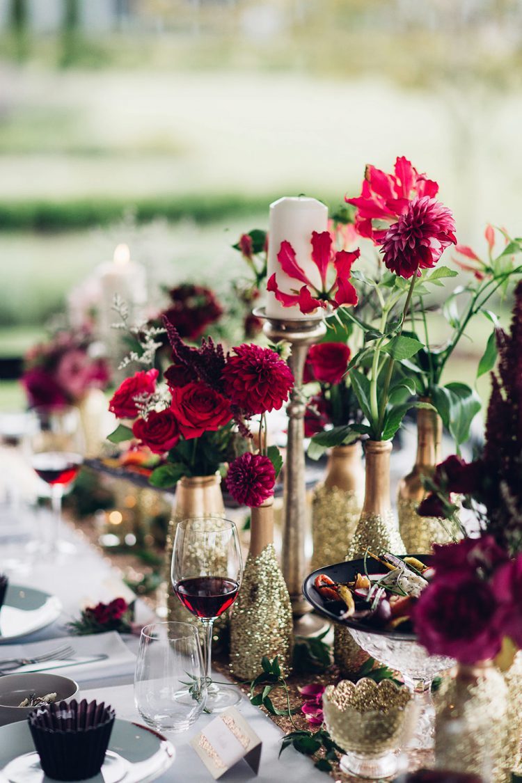 small vases made of gold and gold glitter bottles with bright red blooms and greenery for a festive tablescape