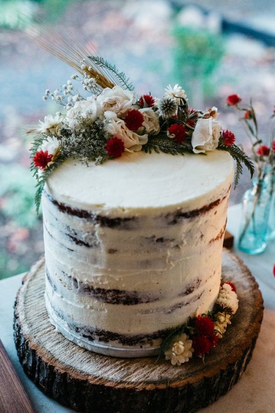 a semi naked wedding cake topped with herbs and blooms for an all-natural look