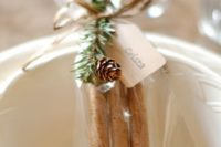 14 cinnamon bark topped with twigs and a pinecone is a  truly Christmas wedding favor