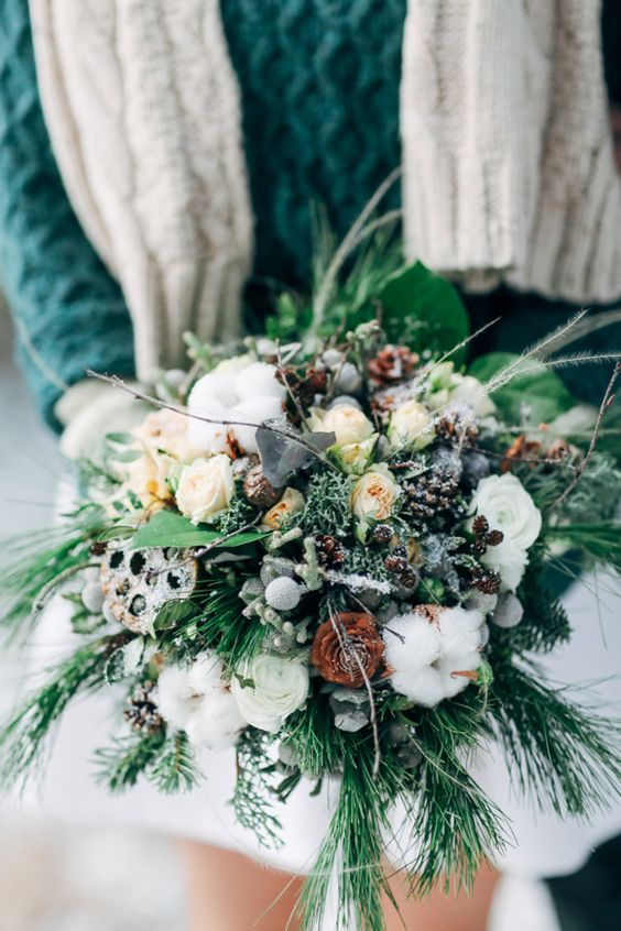 a winter Nordic wedding bouquet with evergreens, berries, cotton, pinecones and neutral blooms for a frozen touch