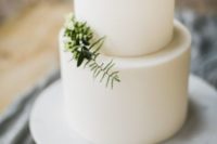 16 a pure white minimalist wedding cake decorated with some greenery for a Scandinavian spring or summer wedding
