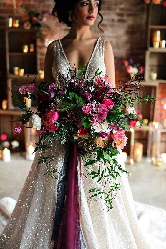 a super lush and refined wedding bouquet in the shades of pink, burgundy, orange, with berries and greenery of various kinds