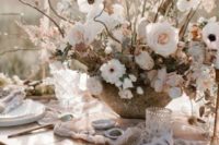 17 a delicate and dimensional wedding centerpiece of white and blush blooms and dired herbs in a cool bowl for a romantic Nordic spring wedding